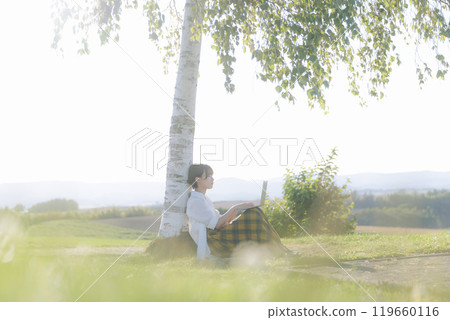 A young woman sitting on a bench and using a laptop 119660116