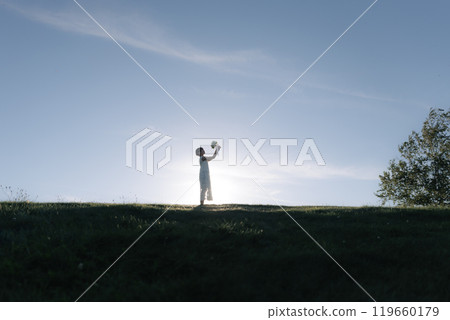 A woman spreading her hands in the meadow 119660179