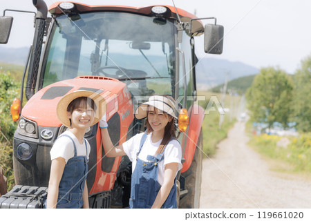 Two young women standing in front of a tractor Two young women standing in front of a tractor 119661020