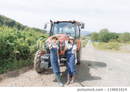 Two young women standing in front of a tractor Two young women standing in front of a tractor 119661024