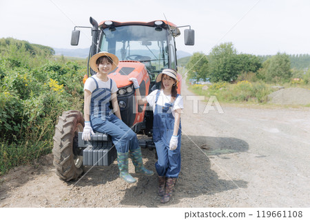 兩個年輕女子站在拖拉機前 119661108