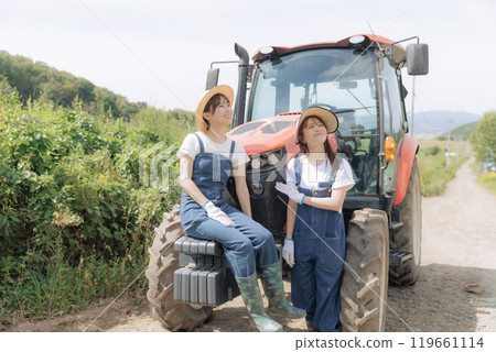 Two young women standing in front of a tractor Two young women standing in front of a tractor 119661114