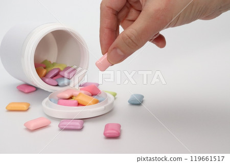A hand picking up a piece of colorful gum A hand picking up a piece of colorful gum 119661517
