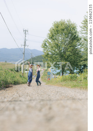 Young women walking along a farm road Young women walking along a farm road 119662535