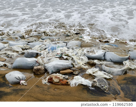 Trash scattered all over the beach close to the ocean Trash scattered all over the beach close to the ocean 119662580