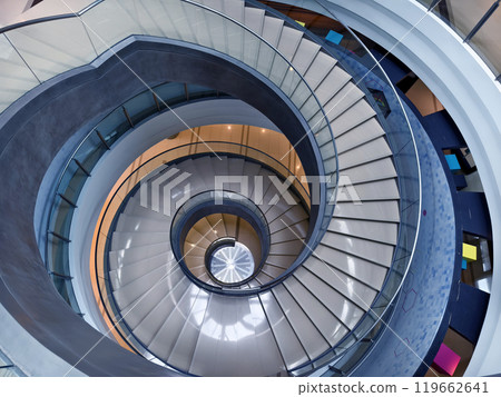 A beautifully designed spiral staircase in a modern building with glass railing A beautifully designed spiral staircase in a modern building with glass railing 119662641