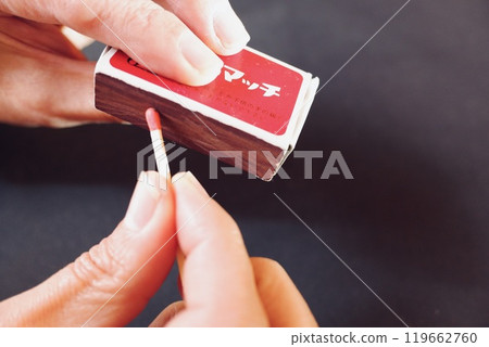 A person striking a match in a matchbox 119662760