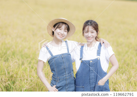 Young women standing in front of a rice field Young women standing in front of a rice field 119662791