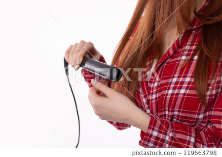 A woman diligently using a hair straightener to achieve the perfect hair styling for her A woman diligently using a hair straightener to achieve the perfect hair styling for her 119663798