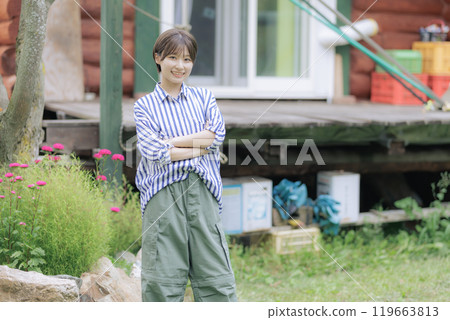 A young woman standing in front of a log house 119663813
