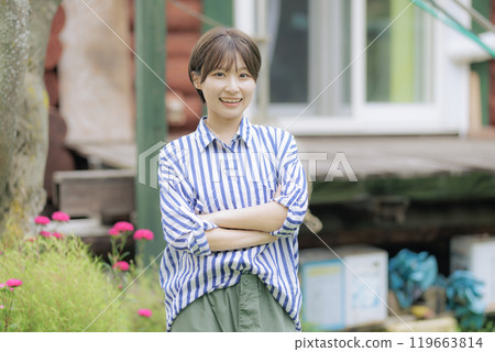 A young woman standing in front of a log house 119663814