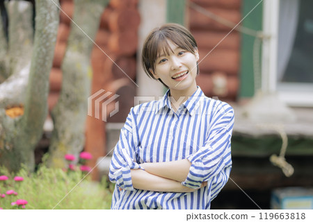 一位年輕女子站在木屋前 一位年輕女子站在木屋前 119663818