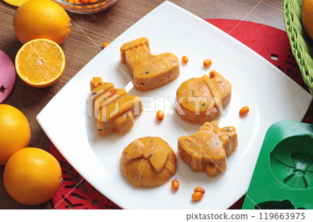 Frozen sea buckthorn and orange tea in Christmas molds on white plate in kitchen. Healthy eating and seasons.  119663975