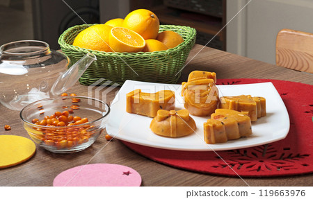 Frozen sea buckthorn and orange tea in Christmas molds on white plate in kitchen. Healthy eating and seasons. Frozen sea buckthorn and orange tea in Christmas molds on white plate in kitchen. Healthy eating and seasons. 119663976
