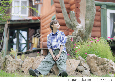 A young woman standing in front of a log house 119664005