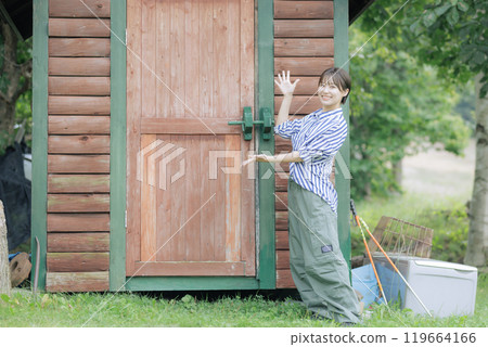 Young woman standing in front of a log house 119664166