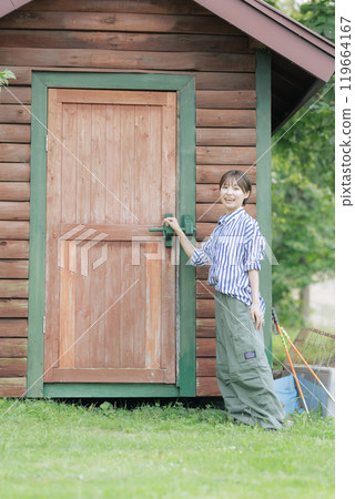 Young woman standing in front of a log house 119664167
