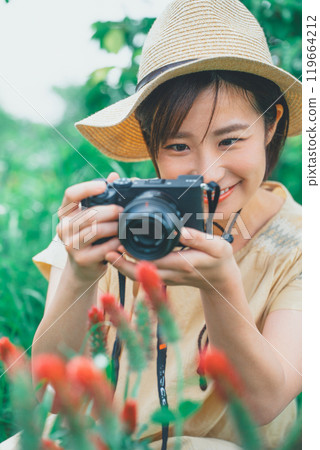 A young woman taking a picture of a strawberry candle with a mirrorless single-lens reflex camera 119664212