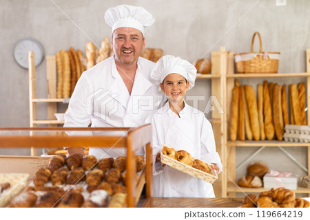 Father baker poses with his young daughter who helps sell fresh bread at bakery Father baker poses with his young daughter who helps sell fresh bread at bakery 119664219