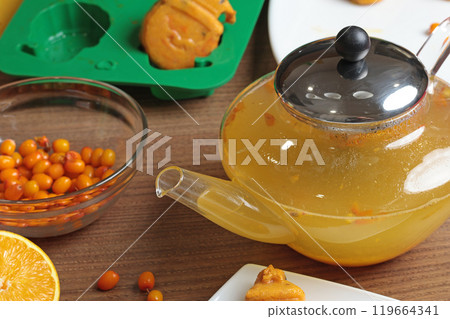 Sea buckthorn, orange and spice tea from frozen briquette in teapot in kitchen. Healthy eating and seasons. Quick batch of beverages. Sea buckthorn, orange and spice tea from frozen briquette in teapot in kitchen. Healthy eating and seasons. Quick batch of beverages. 119664341