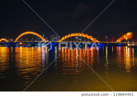 Dragon Bridge over Han River is a famous landmark in the city of Da Nang in Vietnam at night with a golden backlight Dragon Bridge over Han River is a famous landmark in the city of Da Nang in Vietnam at night with a golden backlight 119664401