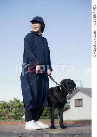 A woman walking with her dog under a blue sky A woman walking with her dog under a blue sky 119664405