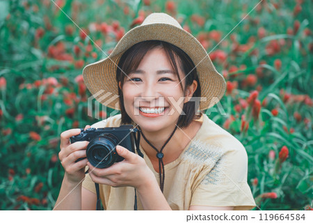 A young woman taking a picture of a strawberry candle with a mirrorless single-lens reflex camera 119664584