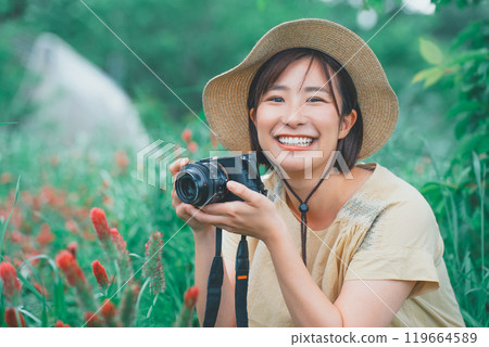 A young woman taking a picture of a strawberry candle with a mirrorless single-lens reflex camera 119664589