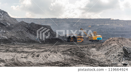 Panoramic view of coal mine. Open pit mine industry, big yellow mining truck for coal quarry. Open coal mining anthracite mining. Pit on coal mining by open way. Rock loading in trucks. Large truck 119664924
