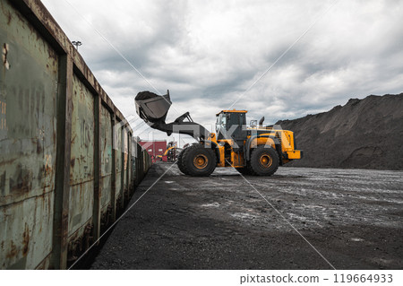 Loading of an loader into railway wagons. Excavator loading coal into wagons. Loading of coal truck using excavator. Shipment coal for transportation by rail Loading of an loader into railway wagons. Excavator loading coal into wagons. Loading of coal truck using excavator. Shipment coal for transportation by rail 119664933