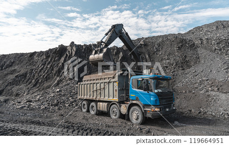 Large quarry dump truck and excavator. Big mining truck work coal deposit. Loading coal into body truck. Production useful minerals. Mining mining machinery to transport coal from open-pit production 119664951