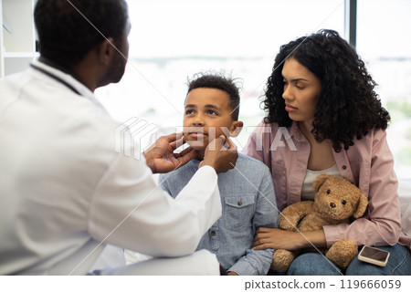 Doctor examining young boy with mother in medical consultation 119666059