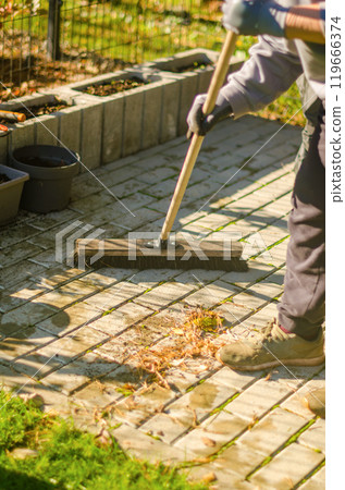 Woman in black trouser pants sweeping concrete patio from autumn leaves . High quality photo Woman in black trouser pants sweeping concrete patio from autumn leaves . High quality photo 119666374