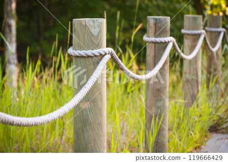 Closeup of fence made of rope and wooden pole in park 119666429