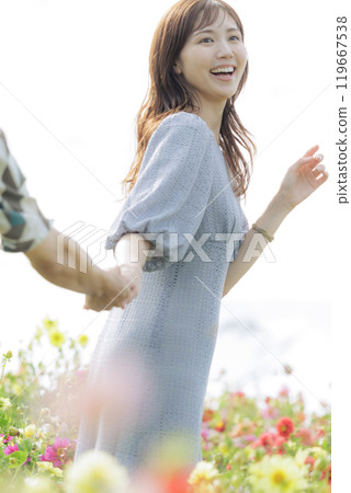 Couple holding hands and walking through a flower field 119667538