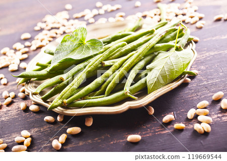 Heap of green pods of raw, not cooked, asparagus beans and white beans on a table Heap of green pods of raw, not cooked, asparagus beans and white beans on a table 119669544