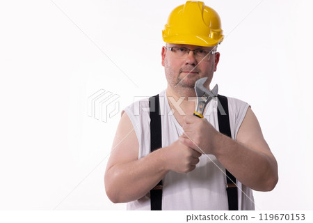 A Construction Worker is holding a Wrench while wearing a Yellow Hard Hat for safety A Construction Worker is holding a Wrench while wearing a Yellow Hard Hat for safety 119670153