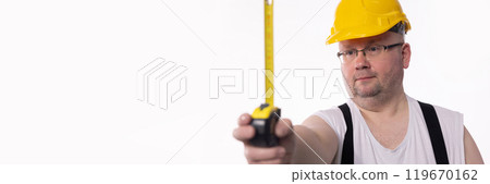 A Construction Worker uses a Measuring Tape and Safety Helmet for protection on the job A Construction Worker uses a Measuring Tape and Safety Helmet for protection on the job 119670162