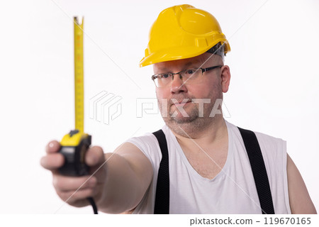 A Construction Worker is meticulously Measuring with a Tape Measure for an upcoming project 119670165