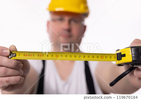 A construction worker diligently using a measuring tape with incredible focus and precision A construction worker diligently using a measuring tape with incredible focus and precision 119670184