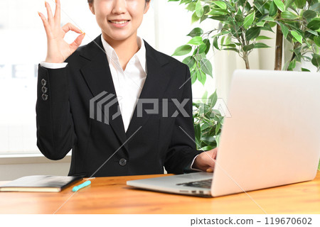 一位身穿西裝的年輕女子在筆記型電腦前擺好姿勢 119670602