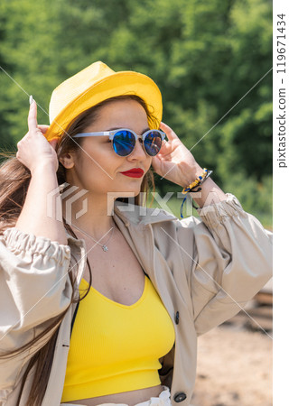 Meeting with the unknown: in a yellow robe, woman looks as if she is preparing to make important journey. Fulfillment of dreams: her cheerful mood symbolizes the endless possibilities that lie ahead. Meeting with the unknown: in a yellow robe, woman looks as if she is preparing to make important journey. Fulfillment of dreams: her cheerful mood symbolizes the endless possibilities that lie ahead. 119671434