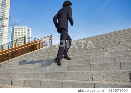 Business image: A young man in a suit running up the stairs 119671694