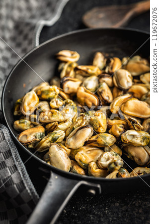 Shelled mussels meat in pan on black table. 119672076