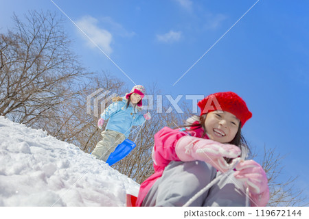 Sisters sledding in a snowy park 119672144