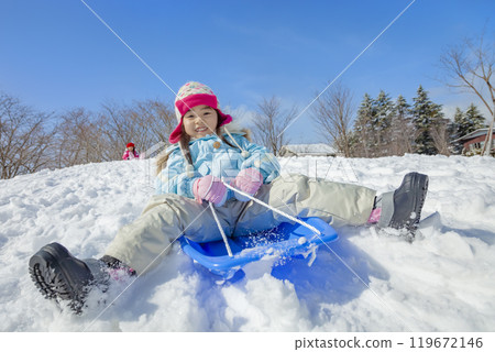Sisters sledding in a snowy park 119672146
