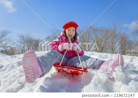 Girl sledding in a snowy park 119672147