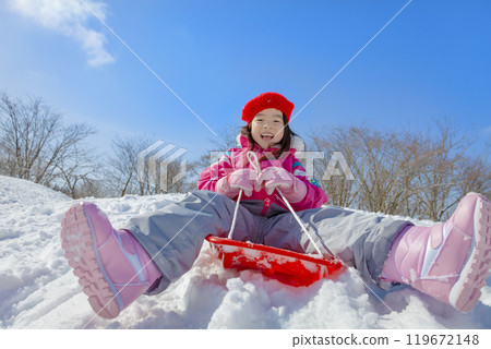 Girl sledding in a snowy park 119672148