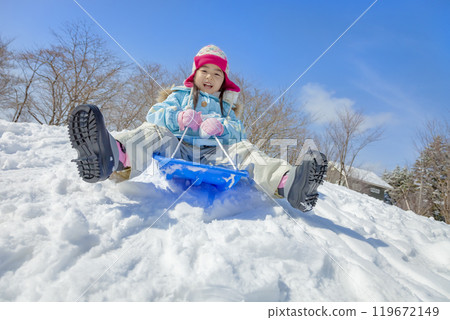 一個女孩在白雪皚皚的公園裡滑雪橇 119672149