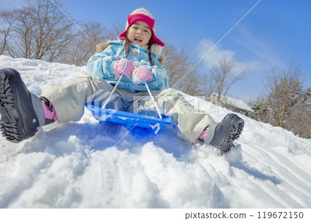 Girl sledding in a snowy park Girl sledding in a snowy park 119672150
